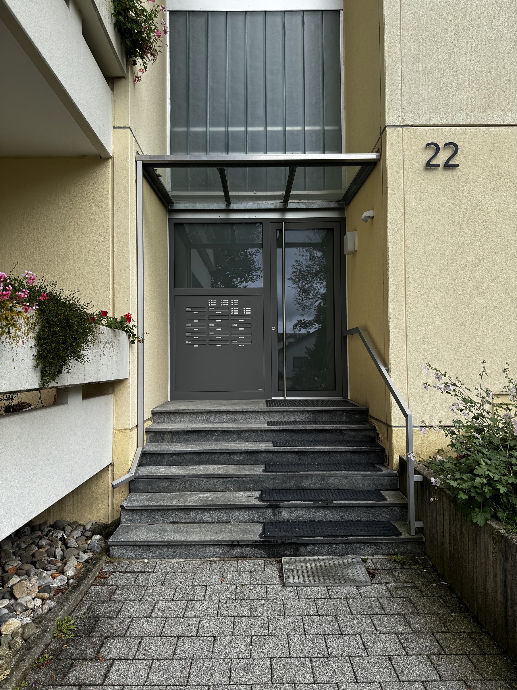 Mehrfamilienhaus-Eingang mit Aluminium-Tür, Briefkastenanlage und Vordach