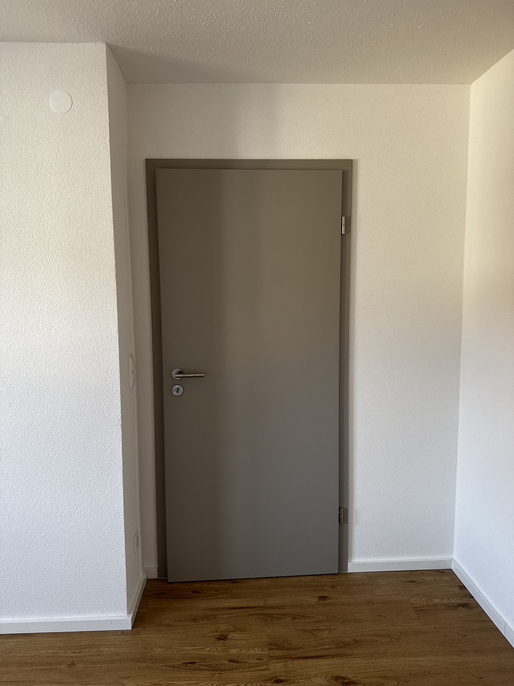Moderne graue Innentür stumpf einschlagend mit Holzboden